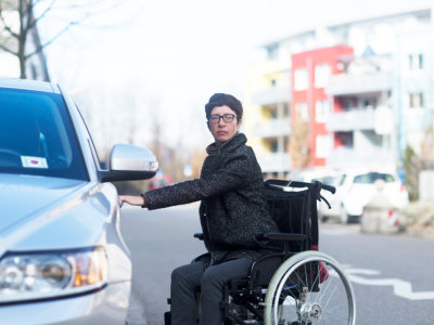 woman in wheelchair holding vehicle door
