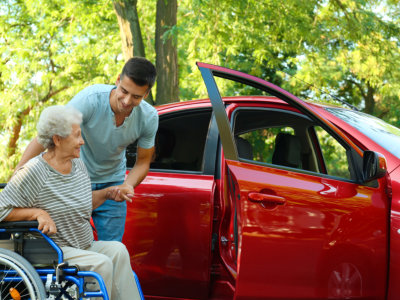 man assisting senior to vehicle