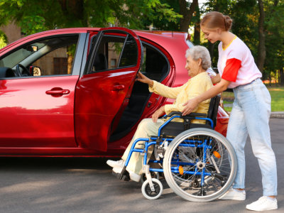woman assisting senior to vehicle